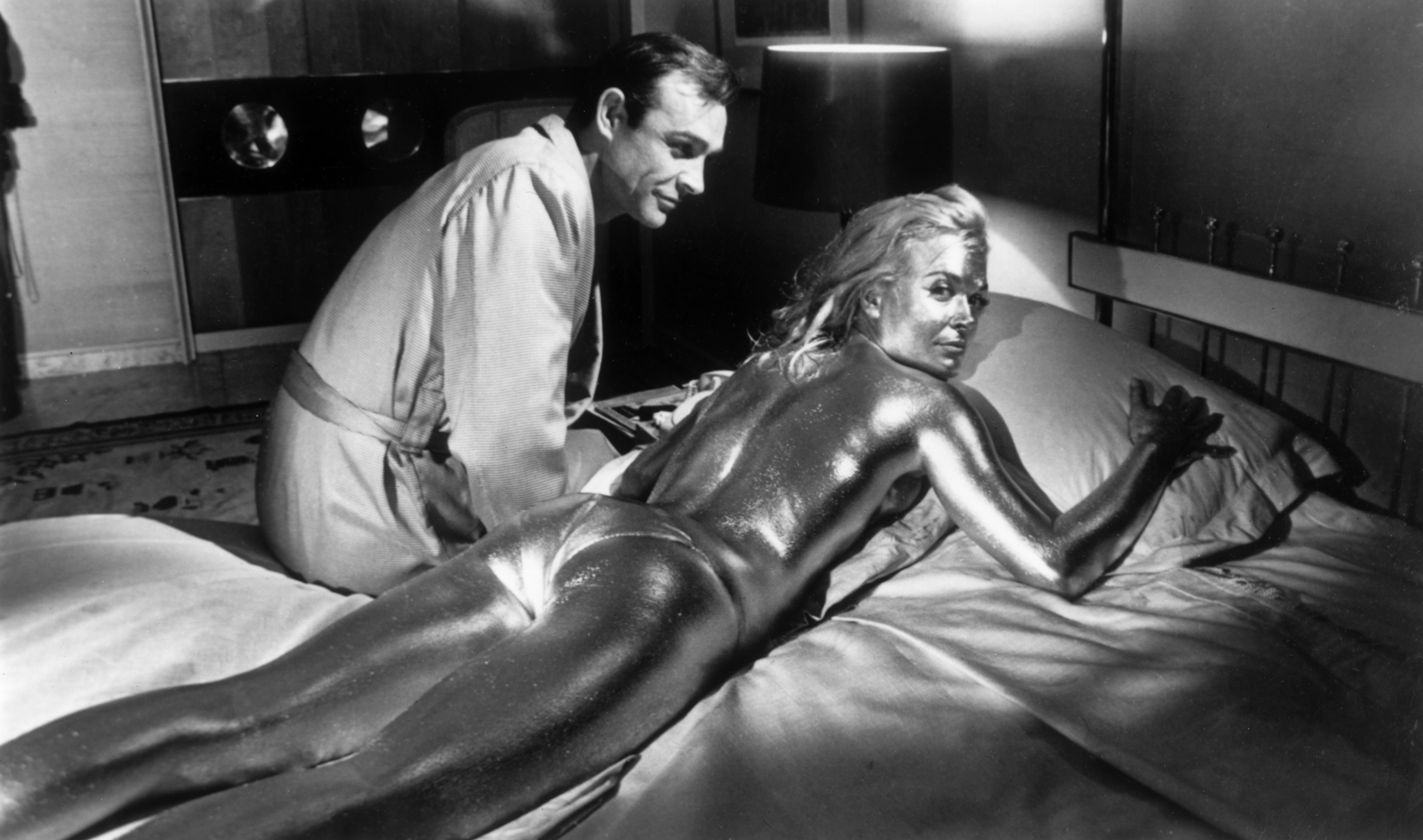 21st April 1964: Sean Connery sitting beside his co-star English actress, Shirley Eaton, covered in gold during the filming of a scene from the James Bond film 'Goldfinger', directed by Guy Hamilton. (Photo by Keystone/Getty Images)