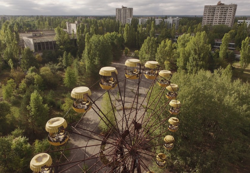 PRIPYAT, UKRAINE - SEPTEMBER 30: In this aerial view an abandoned ferris wheel stands on a public space overgrown with trees in the former city center on September 30, 2015 in Pripyat, Ukraine. Pripyat lies only a few kilometers from the former Chernobyl nuclear power plant and was built in the 1970s to house the plant's workers and their families. On April 26, 1986, technicians at Chernobyl conducting a test inadvertently caused reactor number four to explode, sending plumes of highly radioactive particles and debris into the atmosphere. Authorities evacuated 120,000 people from the area, including 43,000 from Pripyat. Today Pripyat is a ghost-town, its apartment buildings, shops, restaurants, hospital, schools, cultural center and sports facilities derelict and its streets overgrown with trees. The city lies in the inner exclusion zone around Chernobyl where hot spots of persistently high levels of radiation make the area uninhabitable for thousands of years to come. (Photo by Sean Gallup/Getty Images)