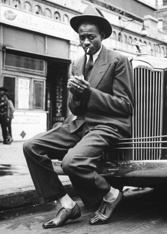 Baseball player Satchel Paige, looking dapper, lighting his cigarette while sitting on front bumper of large car.  (Photo by George Strock/The LIFE Picture Collection/Getty Images)