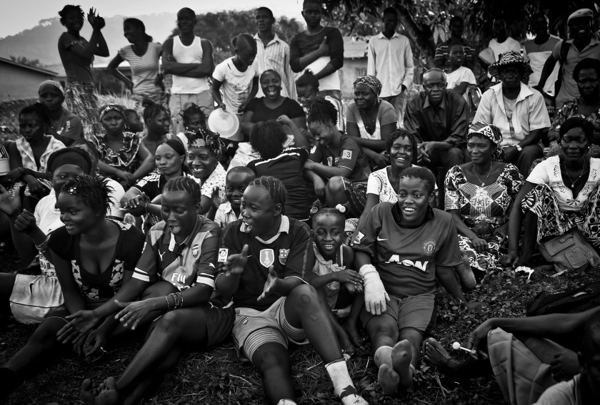 Bandu Turay, second to top row, fourth from right, watches her son Erison, not pictured, play soccer as others cheer for the Ebola Survivor's Soccer Club, on a field near their house, in the city of Kenema, 190 miles east of the capital Freetown, Sierra Leone, Tuesday, April 21, 2015. Last year, 38 members of Erison's family died from the deadly Ebola virus, which has killed over 11,000 across West Africa. Erison founded the Ebola Survivor's Soccer Club as a support network for survivors and a means to battle negative stigmas in the community. (Photo Credit/Tara Todras-Whitehill for the New York Times) World Press Photo 2016 Contest