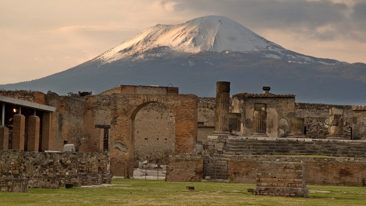 The sun begins to set on the snow capped Mount Vesuvius still overlooking Temple of Jupiter standing in the forum of Pompeii. (DHuss/Creative RF/Getty Images)