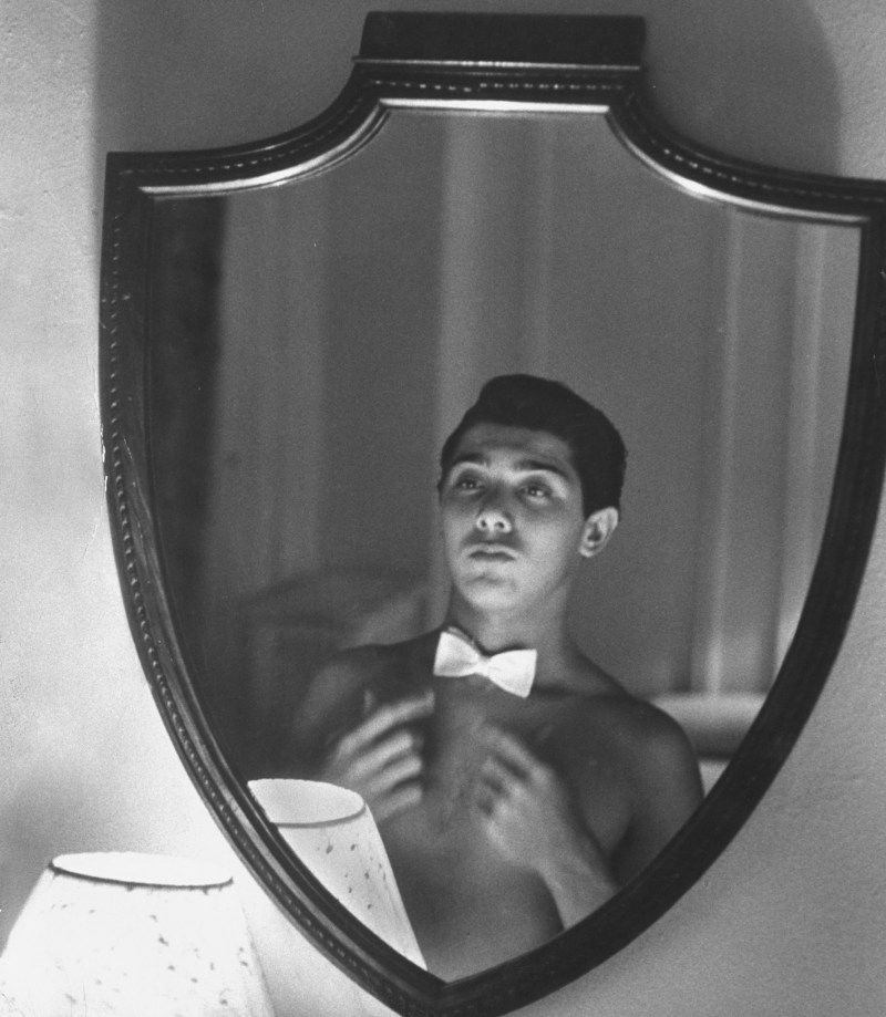 Singer Paul Anka, 19, balancing a white bow tie on his bare collarbone while gazing into mirror before opening at the Copacabana. (Peter Stackpole/The LIFE Picture Collection/Getty Images)
