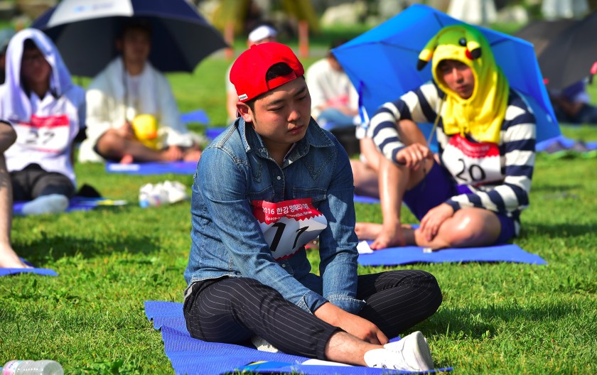 Dozens of citizens take part in Seoul's "space-out" competition in which participants are required to sit idly without talking, sleeping, eating, or using any electronic devices, at a riverside park in Seoul on May 22, 2016. The competition has gained popularity in South Korea since local artists organised the first edition in Seoul in 2014 as a satire of modern life dominated by social media and smartphones. / AFP / JUNG YEON-JE (Photo credit should read JUNG YEON-JE/AFP/Getty Images)