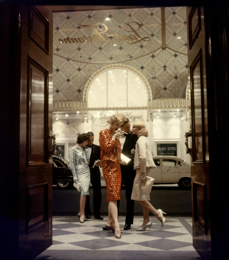 Accompanied by a pair of men in tuxedos, a trio of unidentified fashion models pose in brocade, velvet, and lame 'theater suits' in the entryway of the Lunt-Fontanne Theater, New York, New York, 1958. (Gordon Parks/The LIFE Picture Collection/Getty Images)