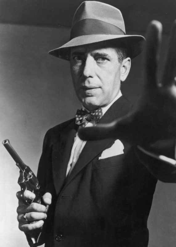 1951: American actor Humphrey Bogart carrying a gun and holding out his hand, in a still from director Bretaigne Windust's film, 'The Enforcer'. (Photo by American Stock/Getty Images)
