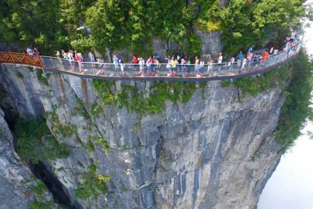 ZHANGJIAJIE, CHINA - AUGUST 01:  Aerial view of tourists walking on the 100-meter-long and 1.6-meter-wide glass skywalk clung the cliff of Tianmen Mountain (or Tianmenshan Mountain) in Zhangjiajie National Forest Park on August 1, 2016 in Zhangjiajie, Hunan Province of China. The Coiling Dragon Cliff skywalk, featuring a total of 99 road turns, layers after another, is the third glass skywalk on the Tianmen Mountain (or Tianmenshan Mountain).  (Photo by VCG/VCG via Getty Images)