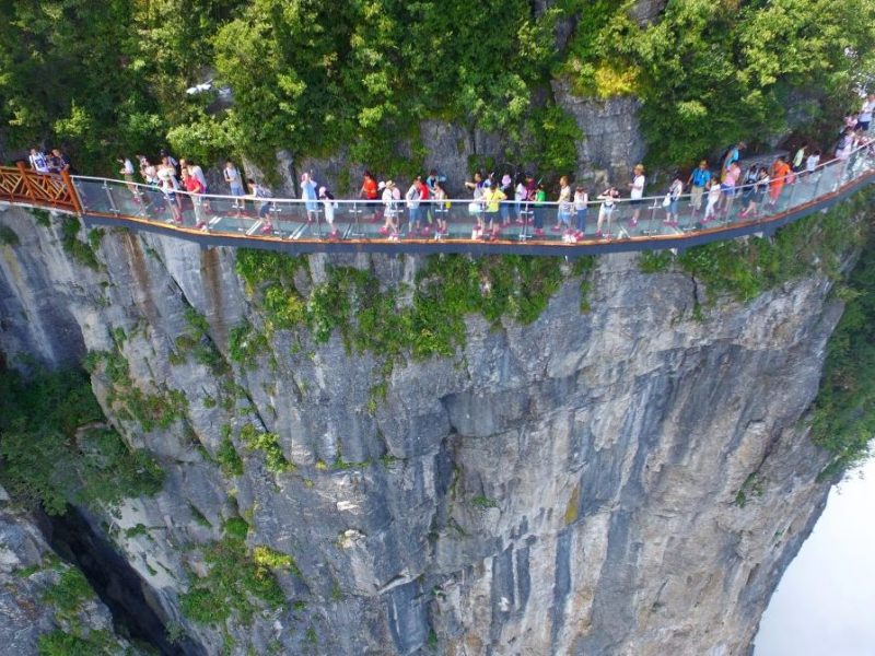 ZHANGJIAJIE, CHINA - AUGUST 01: Aerial view of tourists walking on the 100-meter-long and 1.6-meter-wide glass skywalk clung the cliff of Tianmen Mountain (or Tianmenshan Mountain) in Zhangjiajie National Forest Park on August 1, 2016 in Zhangjiajie, Hunan Province of China. The Coiling Dragon Cliff skywalk, featuring a total of 99 road turns, layers after another, is the third glass skywalk on the Tianmen Mountain (or Tianmenshan Mountain). (Photo by VCG/VCG via Getty Images)