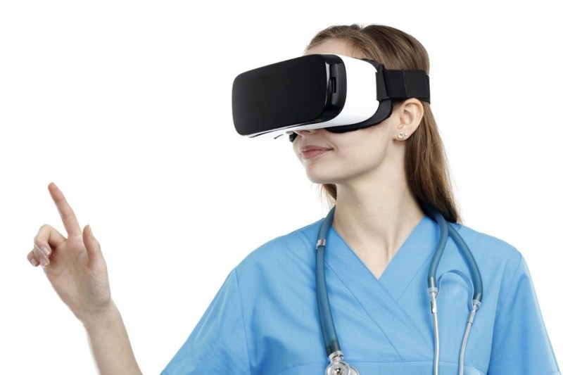 Young female doctor diving in to virtual reality world with VR device.