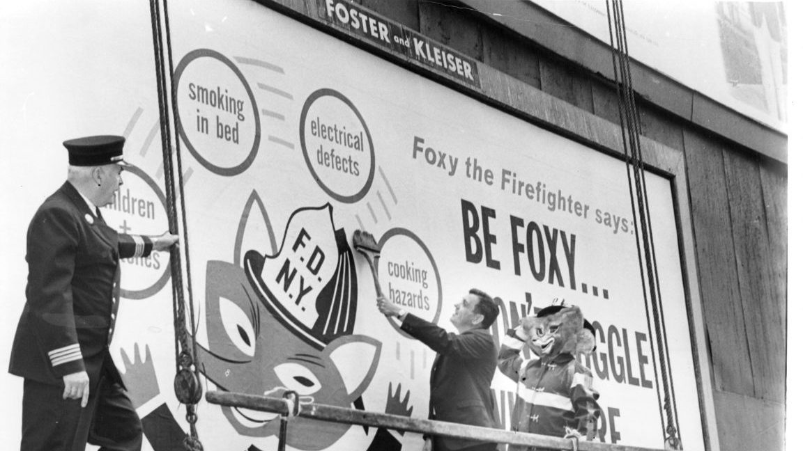 What Smokey the Bear is to the prevention of forest fires, City officials hope Foxy the Fireman will be to human safety. Fire Commissioner Thompson (c) puts the finishing touches to one of 250 billboard signs posted around the city to warn against home fire hazarsd. Looking on are Asst. Chief Charles McKeogh (l) and Foxy himself, played by fireman Barney Schmeltzer. (Photo by William Jacobellis/New York Post Archives / (c) NYP Holdings, Inc. via Getty Images)