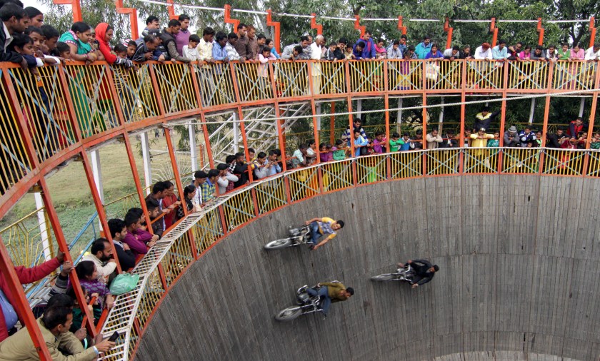 Stuntmen perform on the motor bikes as villagers watch the show of 'Maut ka Kuan or Well of Death' during the annual Jhiri Fair at Kanachack village on the outskirts of Jammu, on November 25, 2015 in Jammu, India. (Nitin Kanotra/Hindustan Times via Getty Images)
