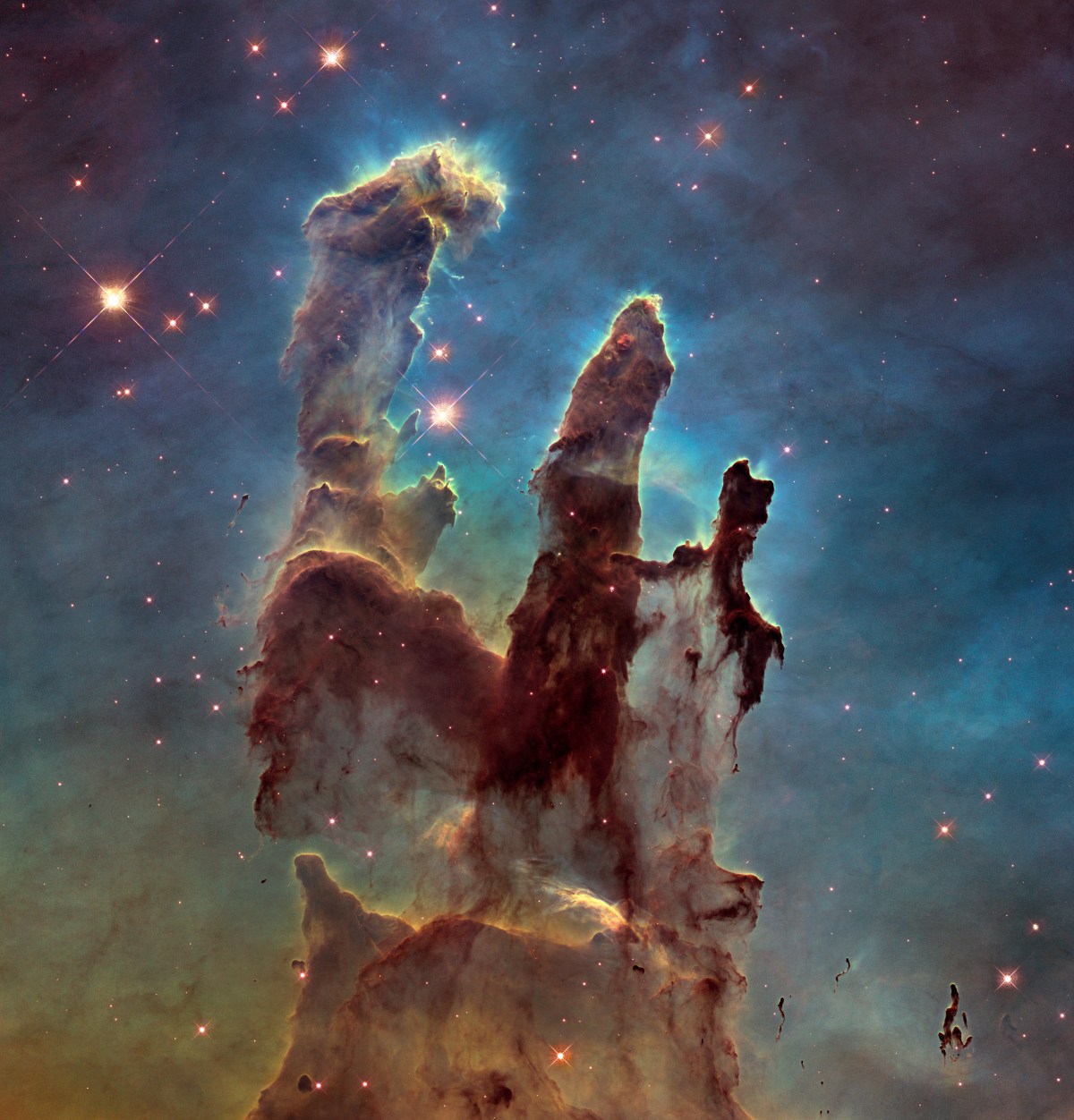 The NASA/ESA Hubble Space Telescope has revisited one of its most iconic and popular images: the Eagle Nebula’s Pillars of Creation. This image shows the pillars as seen in visible light, capturing the multi-coloured glow of gas clouds, wispy tendrils of dark cosmic dust, and the rust-coloured elephants’ trunks of the nebula’s famous pillars. The dust and gas in the pillars is seared by the intense radiation from young stars and eroded by strong winds from massive nearby stars. With these new images comes better contrast and a clearer view for astronomers to study how the structure of the pillars is changing over time.