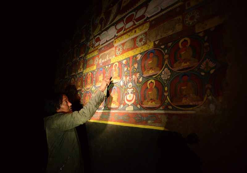 In this photograph taken on June 15, 2016, Nepalese artist Tsewang Jigme points to a damaged area of a wall painting during an interview with AFP in Lo Manthang in Upper Mustang. Deep in the heart of a medieval monastery in Nepal's remote Upper Mustang region, the battle to restore sacred murals and preserve traditional Tibetan Buddhist culture is in full swing. / AFP / PRAKASH MATHEMA / To go with 'Nepal-Tibet-Buddhism-Architecture-Painting' FEATURE by Ammu Kannampilly (Photo credit should read PRAKASH MATHEMA/AFP/Getty Images)