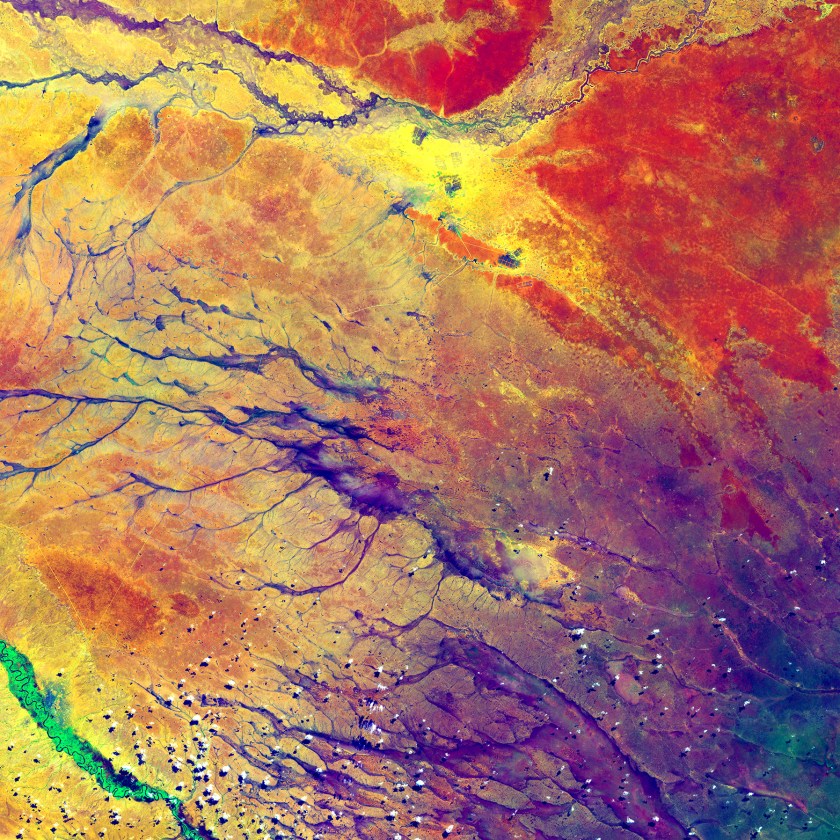 The deep purple in the lower right spreads out into a few channels before fading into a multitude of colors. These channels are remnants of an ancient drainage network in Kenya. The beauty of the colors actually hides a stark reality for hundreds of thousands of people. The dark spots at the top center of the image are refugee camps (USGS/NASA)