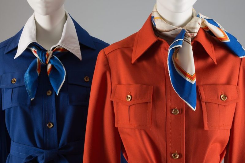 Cobalt blue TWA uniform; jacket, skirt & belt in wool; shirt style jacket with tie belt; A-line skirt with stitched & released pleats at front TWA uniform; jacket, belt, pants in wool; orange shirt style jacket with tie belt; beige wide leg pants with woven stripe in red, blue & yellow