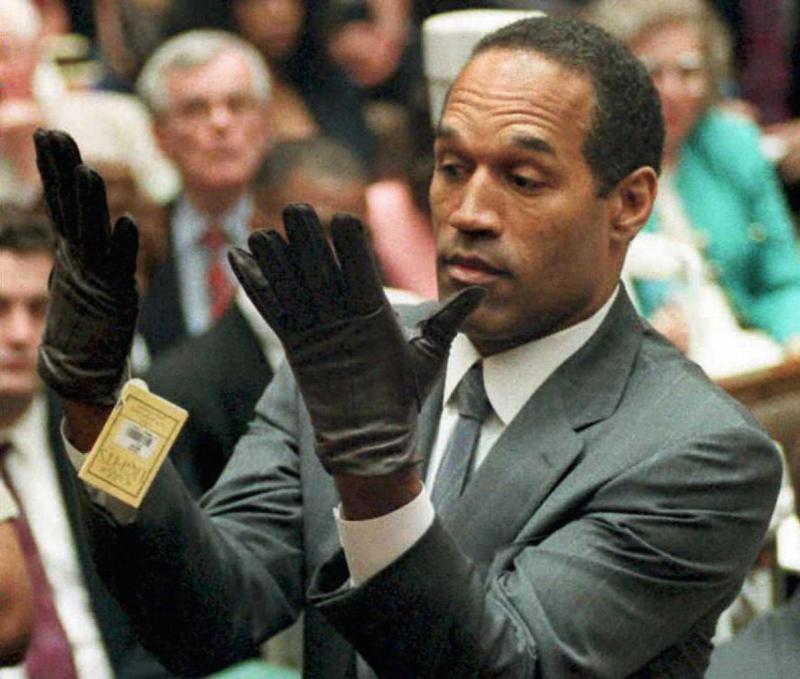 Los Angeles, UNITED STATES: (FILES): This 21 June 1995 file photo shows former US football player and actor O.J. Simpson looking at a new pair of Aris extra-large gloves that prosecutors had him put on during his double-murder trial in Los Angeles. Media tycoon Rupert Murdoch announced 20 November 2006 the cancellation of a controversial book and television interview involving O.J. Simpson being planned by his News Corp company. AFP PHOTO/Vince BUCCI/FILES (Photo credit should read VINCE BUCCI/AFP/Getty Images)
