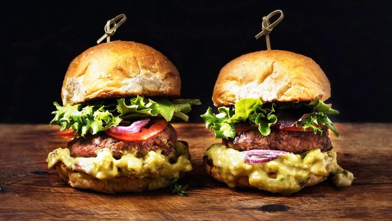 Two burgers on a rustic wooden table