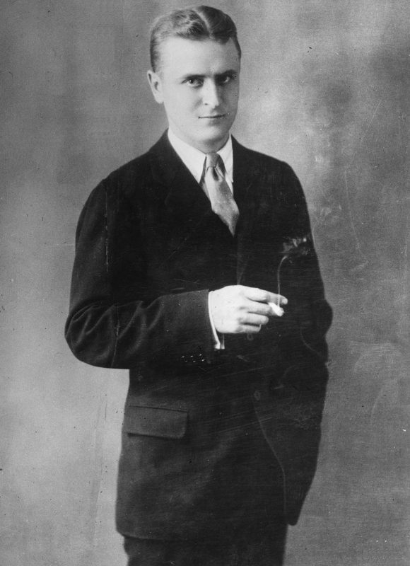 1925:  A studio portrait of American writer F. Scott Fitzgerald (1896 - 1940) wearing a suit and tie and holding a lighted cigarette.  (Photo by Hulton Archive/Getty Images)