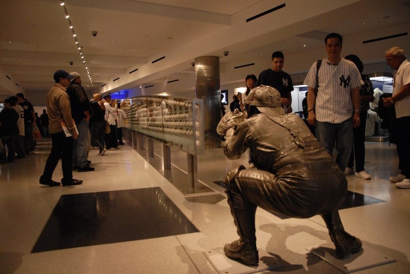 NEW YORK - APRIL 18, 2009: Fans look at the collection of autographed baseballs mounted within the case that stands under the arc of the path of the final pitch to catcher Yogi Berra #8 of pitcher Don Larsen's perfect game during Game Five of the World Series in 1956 as represented in a sculpture within the Yankees Museum during a game on April 18, 2009 between the Cleveland Indians and the New York Yankees at Yankee Stadium in New York, New York. (Photo by: Diamond Images/Getty Images)
