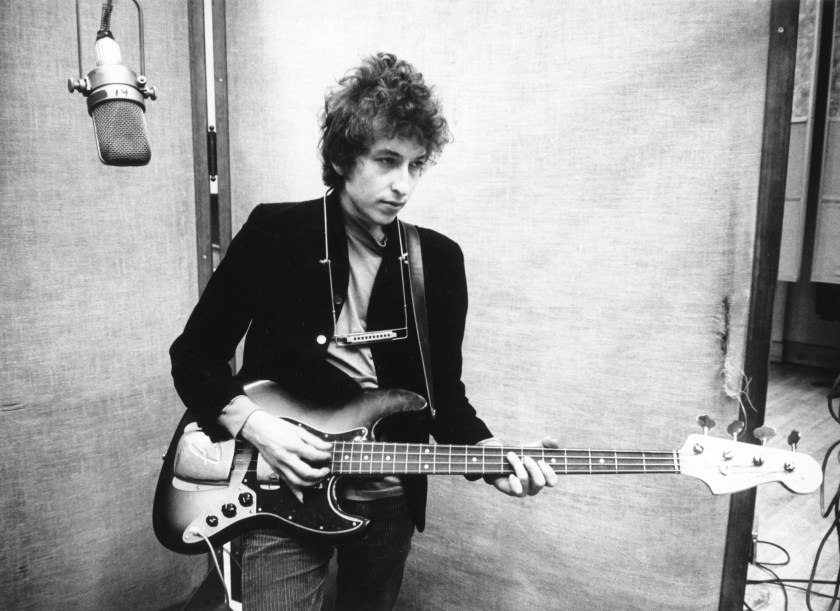 Bob Dylan sing in to a microphone with a harmonica around his neck to record his album 'Bringing It All Back Home' on January 13-15, 1965 in Columbia's Studio A in New York City, New York. (Michael Ochs Archives/Getty Images)