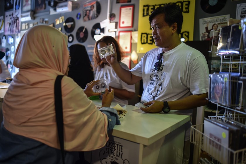 This picture taken on October 8, 2016 shows Mohammad Radzi Jasni (R), owner of Teenage Head Records, showing an audio cassette to a customer during 'International Cassette Store Day' in Subang Jaya, on the outskirts of Kuala Lumpur. Vinyl's renaissance is well-documented and now it seems cassettes are rising from the grave, with artists such as Kanye West and Justin Bieber releasing songs on tape. In Southeast Asia low production costs and a retro-cool image have made cassettes an underground-music fixture, especially for struggling bands getting their name out. (Mohd Rasfan/AFP)