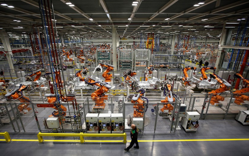 An employee watches as a ABB Ltd. automated robots work on Mini automobile parts, produced by Bayerische Motoren Werke AG (BMW), as they move along the production line at the company's Cowley plant in Oxford, U.K., on Monday, Nov. 18, 2013. (Simon Dawson/Bloomberg via Getty Images)