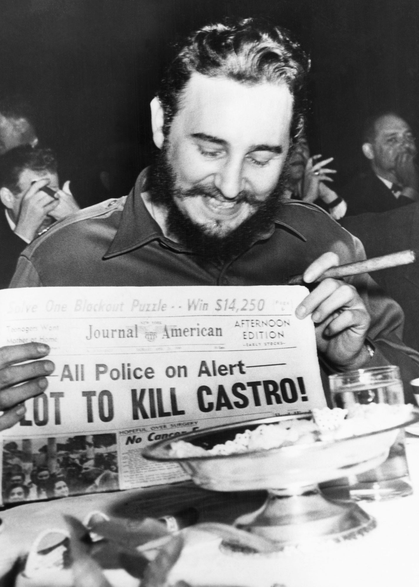 (Original Caption) Seems amused by assassination plot...Seeming quite amused, Cuban Prime Minister Fidel Castro holds up a newspaper headlining the discovery of a plot to kill Castro here, April 23rd. Castro was at the Overseas Press Club at the time. Police said five brothers had been sent here from Philadelphia, Pa., to assassinate the bearded leader. Police said that three other men, including a sixth brother, were believed to be in New York in connection with the plot to kill Castro. Earlier in the day, when asked about a reported assassination attempt, Castro had replied, "In Cuba, they had tanks, planes and they run away. So what are they going to do here? I sleep well and don't worry at all." (Bettmann/Contributor/Getty Images)