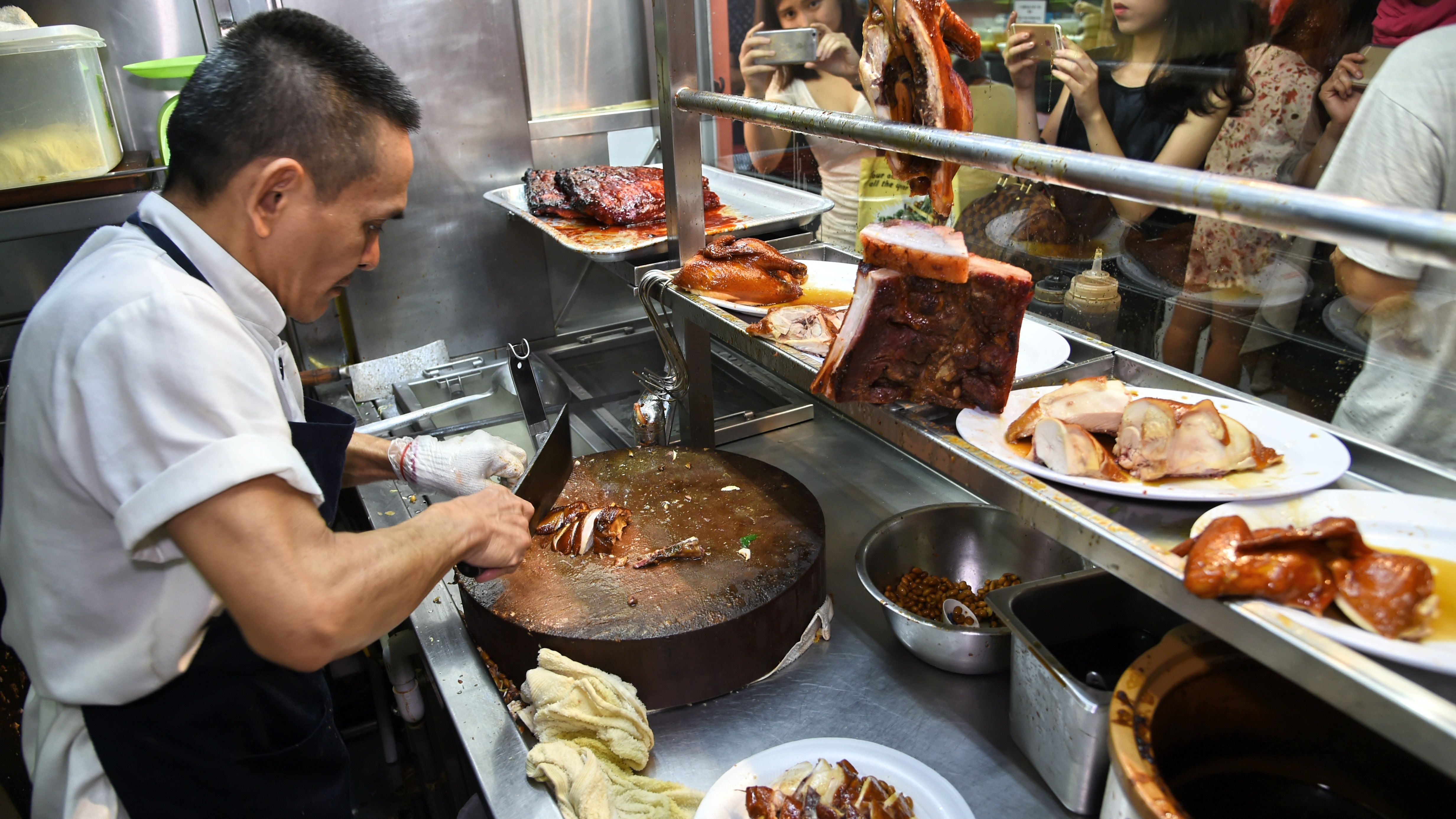 This photo taken on July 26, 2016 shows Singaporean hawker Chan Hon Meng chopping braised chicken at his Hong Kong Soya Sauce Chicken Rice and Noodle stall in Singapore.
Chan is one of two "hawkers" -- so-called because many started out as street peddlers -- awarded one star by the culinary bible Michelin, when it launched its inaugural Singapore guide in late July. / AFP / ROSLAN RAHMAN / TO GO WITH Lifestyle Singapore food Michelin,FEATURE by Elizabeth Law (Photo credit should read ROSLAN RAHMAN/AFP/Getty Images)