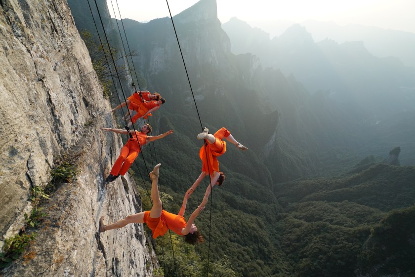 Dancers from American Bandaloop dance troupe hang from the plank road on Guigu Cliff to perform in the air at Tianmenshan National Forest Park on September 12, 2016 in Zhangjiajie, Hunan Province of China. Bandaloop dance troupe made performances in the air at Tianmenshan National Forest Park on Sep 12-13 in Zhangjiajie. Dancers hung on Guigu Cliff, Tianmen Cave and Yuhu Peak to perform the "vertical dance". (Basil Tsimoyanis/VCG)