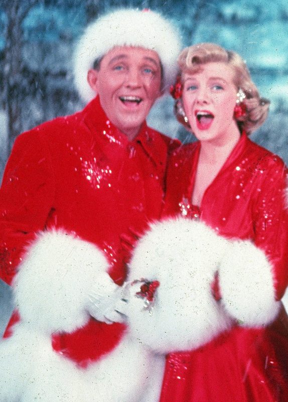 American actors Bing Crosby, Rosemary Clooney, Vera-Ellen, and Danny Kaye sing together, while dressed in fur-trimmed red outfits and standing in front of a stage backrop, in a scene from the film 'White Christmas,' directed by Michael Curtiz, 1954. (John Swope/The LIFE Images Collection/Getty Images)