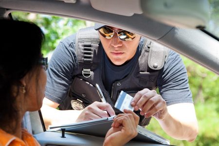 A police officer stops a driver to give her a traffic ticket for speeding. (Getty Images)