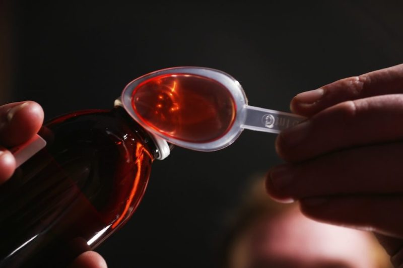 Man pouring cough mixture onto plastic spoon (Photo by Universal Images Group via Getty Images)