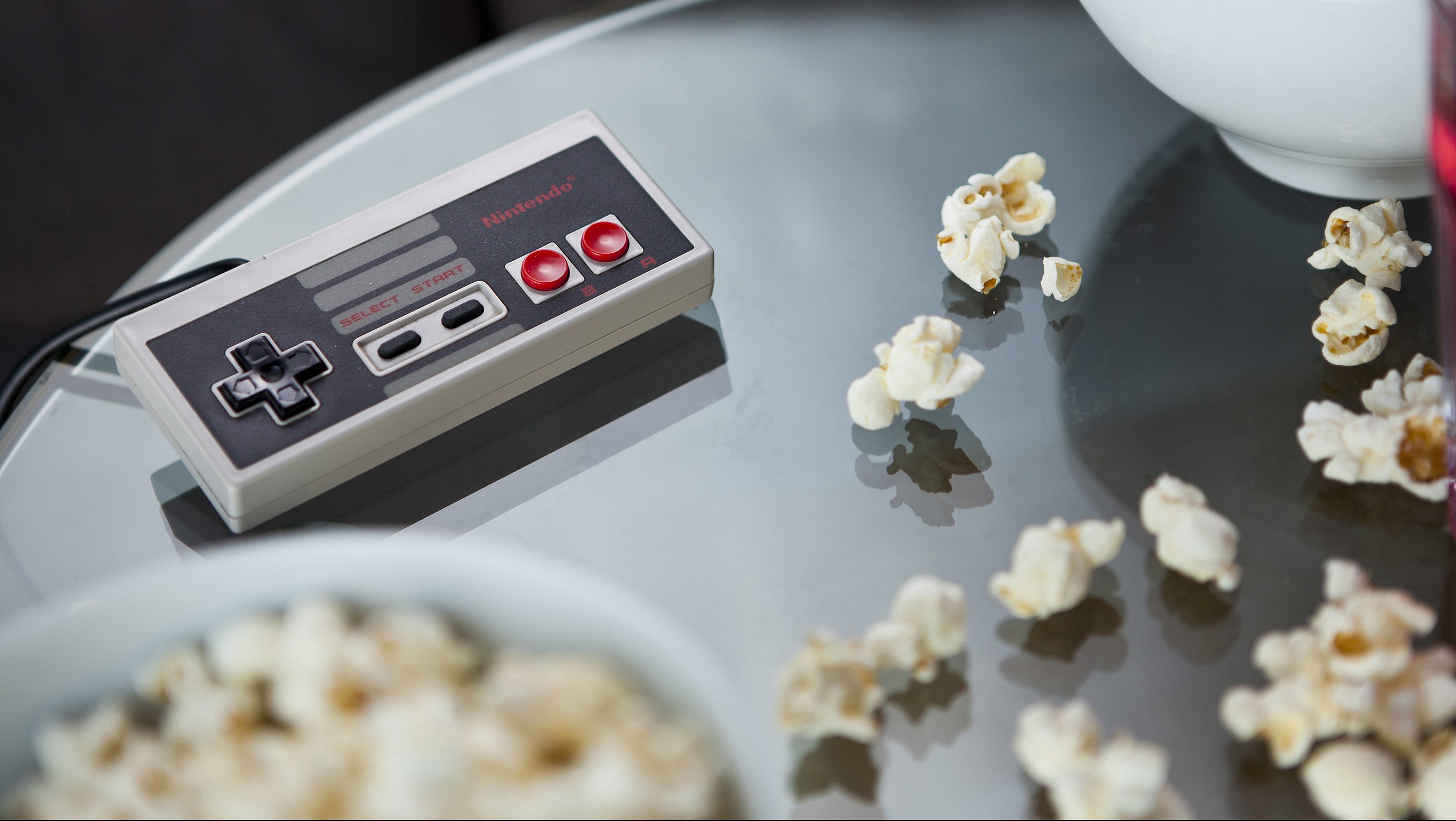 A vintage Nintendo NES controller photographed on a glass table, surrounded by bowls of snacks, taken on July 9, 2013. (Philip Sowels/Future Publishing via Getty Images)