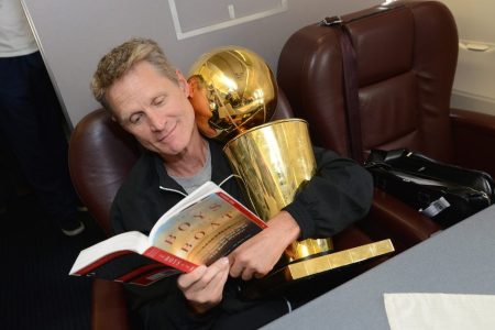 OAKLAND, CA - JUNE 17:  Steve Kerr of the Golden State Warriors holds the NBA trophy on the plane as the team travels home from Cleveland after winning the 2015 NBA Finals on June 17, 2015 in Oakland, California. NOTE TO USER: User expressly acknowledges and agrees that, by downloading and/or using this Photograph, user is consenting to the terms and conditions of the Getty Images License Agreement. Mandatory Copyright Notice: Copyright 2015 NBAE (Photo by Noah Graham/NBAE via Getty Images)