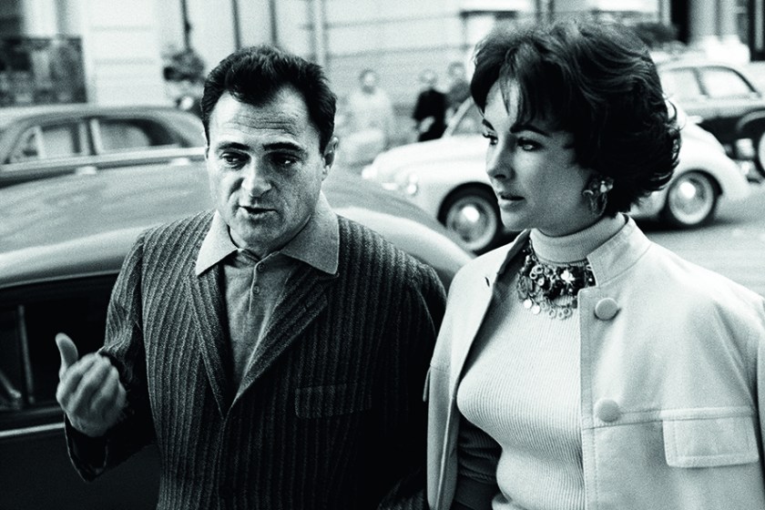 En route from Belgrade to Madrid after their successful Russian tour, Mike Todd and his wife Elizabeth Taylor, flying in their private airplane, ran into engine trouble over the Mediterranean in 1958. They were forced to fly into Nice on only one engine, and fortunately landed safely. Forced to wait for their plane to be repaired, they decide to go over and visit Monte Carlo. While Mike Todd talks with some local journalists, Liz goes to Cartier and buys a pair of beautiful earrings. (Riviera Cocktail, Edward Quinn - Côte d'Azur Jet Set of the 1950s, Small Format Edition, to be published by teNeues)