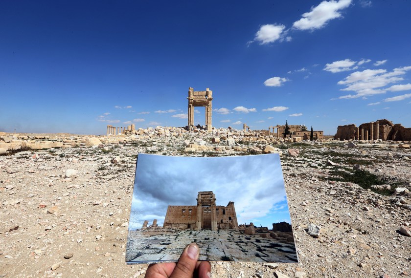 A general view taken on March 31, 2016 shows a photographer holding his picture of the Arc du Triomphe (Triumph's Arch) taken on March 14, 2014 in front of the remains of the historic monument after it was destroyed by Islamic State (IS) group jihadists in October 2015 in the ancient Syrian city of Palmyra. (Joseph Eid/AFP/Getty Images)