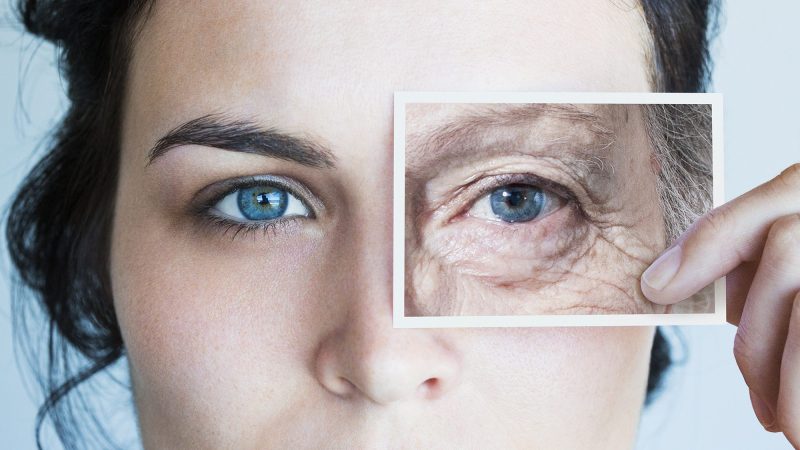 Young woman with photo of aged eye over her own