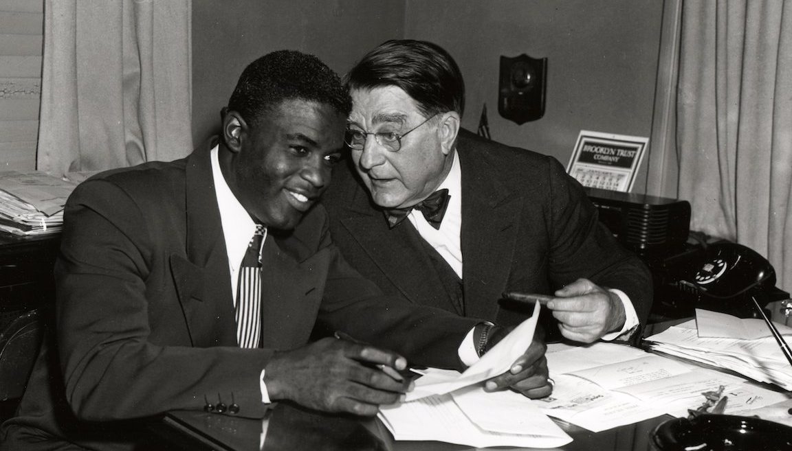 BROOKLYN - 1949.  Jackie Robinson, left, and Branch Rickey share a joke during a contract signing session in the front offices of the Brooklyn Dodgers at Ebbets Field in Brooklyn in 1949.   (Photo by Mark Rucker/Transcendental Graphics, Getty Images)