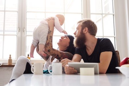 Mother and father with newborn baby sitting in their kitchen and having fun together (Getty Images)