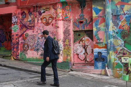 A pedestrian passes in front of walls displaying graffiti and pichacao in Sao Paulo, Brazil (Patricia Monteiro/Bloomberg)