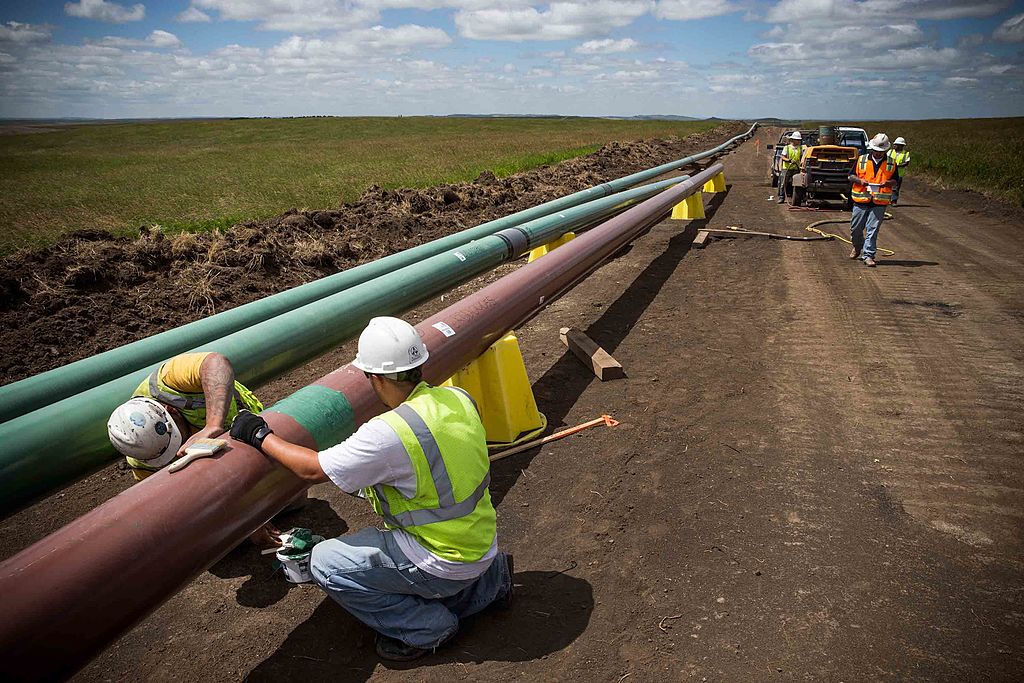 Construction workers specializing in pipe-laying work on a section of pipeline on July 25, 2013 outside Watford City, North Dakota. (Photo by Andrew Burton/Getty Images)