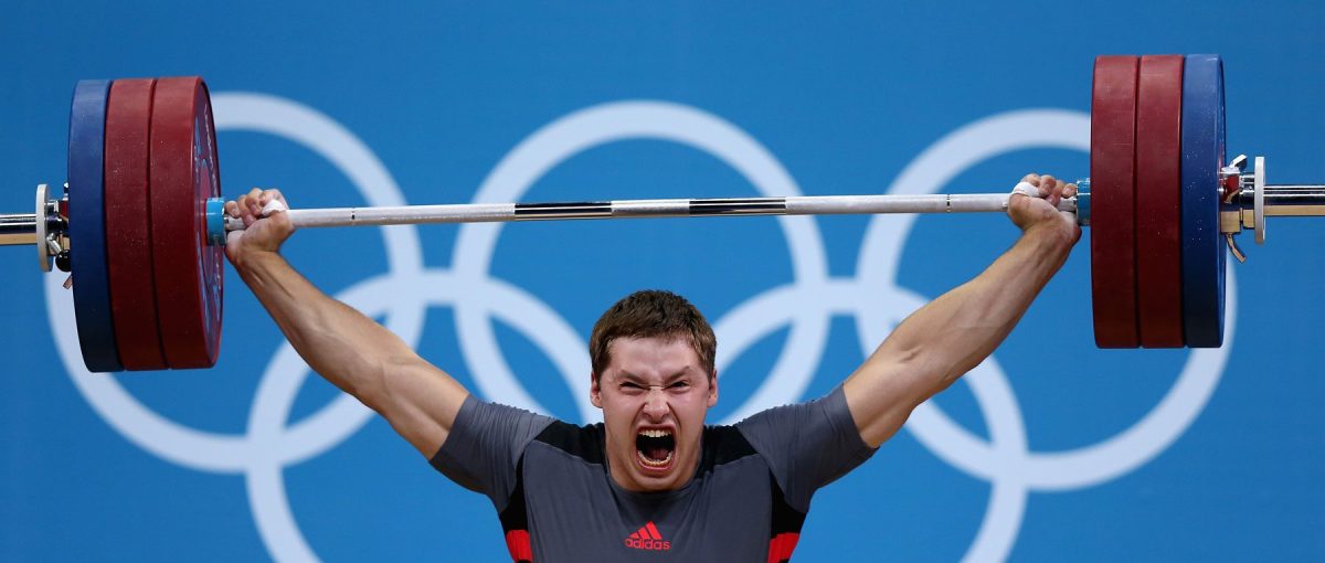 Professional weight lifter screaming while holding heavy weight