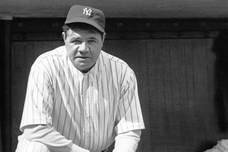 Babe Ruth in his Yankees uniform stands on dugout steps