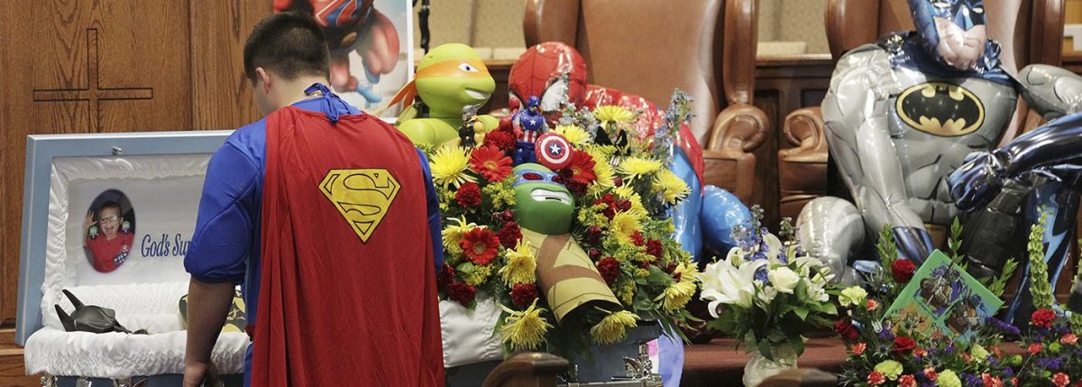 Dale Hall, dressed as Superman, stands before the casket during a superhero-themed funeral service for his brother, Jacob Hall at Oakdale Baptist Church on Wednesday, Oct. 5, 2016, in Townville, S.C.
