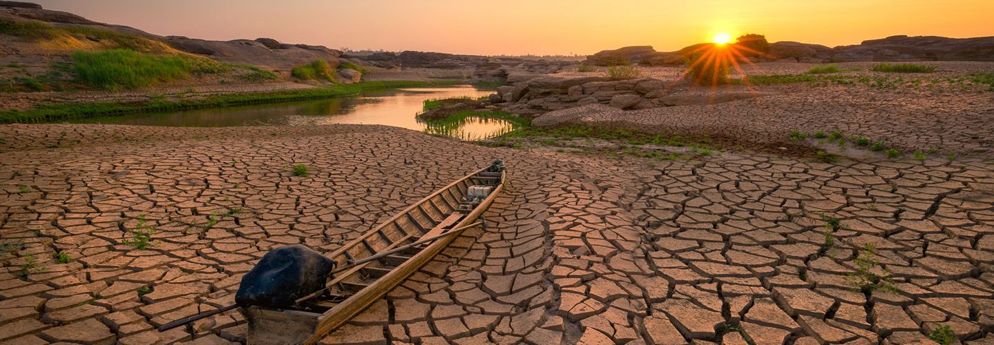 Wooden boat on drought land with sunrise.