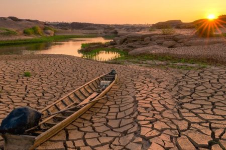 Wooden boat on drought land with sunrise.