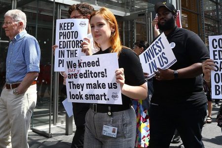 New York Times (NYT) employees hold banners during a temporary strike against downsizing and dismissal plans of the NYT management outside of New York Times building in New York, United States on June 29, 2017.