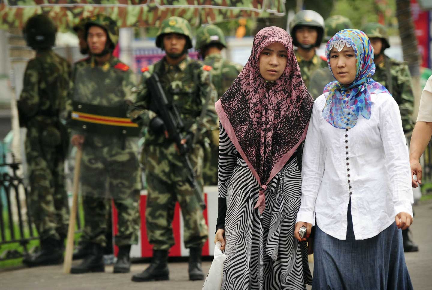 Two ethnic Uighur women pass Chinese paramilitary policemen standing guard outside the Grand Bazaar in the Uighur district of the city of Urumqi in China's Xinjiang region on July 14, 2009. (Peter Parks/AFP/Getty Images)