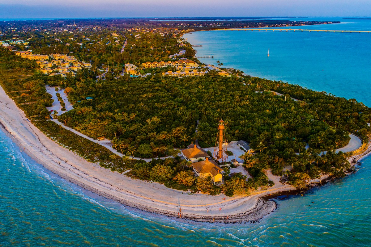 An aerial view of Sanibel Island in Florida at sunset, showing the Sanibel Lighthouse on the east end of the island. Here's why we think it's a great vacation destination.