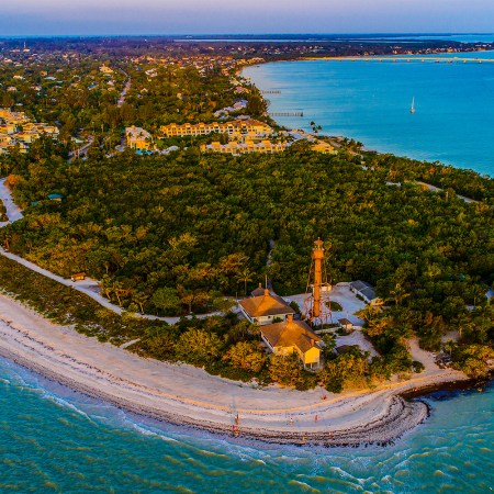 An aerial view of Sanibel Island in Florida at sunset, showing the Sanibel Lighthouse on the east end of the island. Here's why we think it's a great vacation destination.