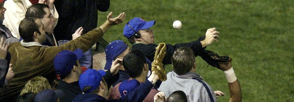 In this Oct. 14, 2003 file photo, Chicago Cubs left fielder Moises Alou's arm is seen reaching into the stands, at right, unsuccessfully for a foul ball along with a fan identified as Steve Bartman, left, wearing headphones, glasses and Cubs hat, during the eighth inning against the Florida Marlins in Game 6 of the National League Championship Seriesin Chicago.